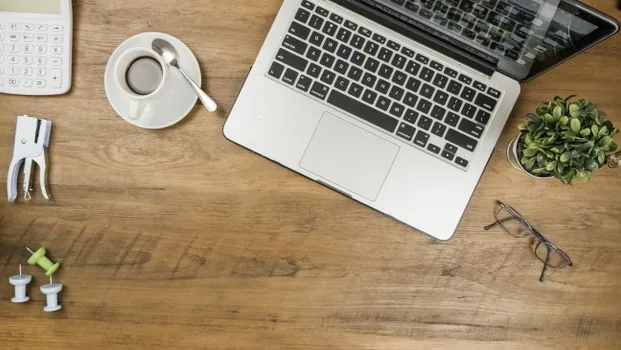 a calculator, a notebook and a calm cup of coffee on a wooden cafe counter, soft morning window light, a small business owner doing paperwork, close-up, editorial photography, shallow depth of field