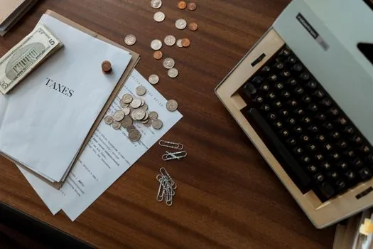 a calculator and a tax notice paper on a desk next to a coffee cup, warm soft light, an air of worry, editorial photography, shallow depth of field, no text