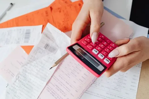 a calculator next to neatly stacked invoices and a coffee cup on a clean desk, soft natural light, financial paperwork concept, editorial still life photography