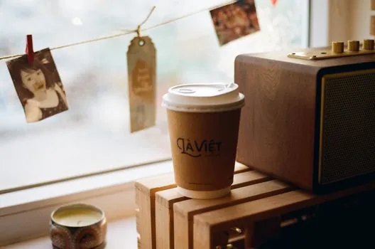 a close-up of a food delivery settlement statement on paper next to a calculator and a cup of coffee on a wooden restaurant counter, warm afternoon light, korean small business interior, editorial photography, shallow depth of field