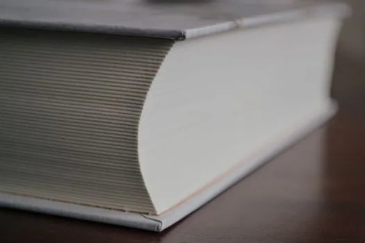 a simple handwritten household-style account book next to a thick formal accounting ledger on a desk, soft window light, editorial photography, shallow depth of field, no text