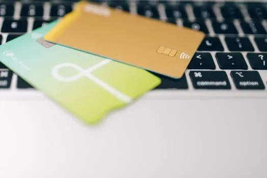 a single credit card placed on a small business receipt next to a laptop showing a spreadsheet, clean desk, soft natural light, editorial photography, shallow depth of field