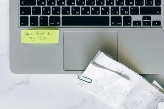 a small Korean shop owner's desk with a laptop showing a tax filing screen, a calculator and receipts, warm afternoon light through the window, editorial photography, shallow depth of field