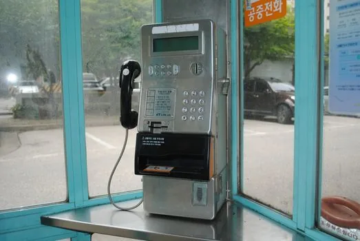 a small Korean storefront counter with a card payment terminal and a stack of utility bills, soft natural window light, editorial photography, shallow depth of field, no text