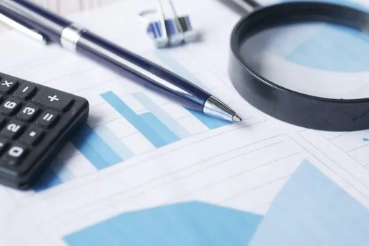 a calculator, a pen and a loan repayment plan document on a wooden desk, soft natural window light, close-up, no text, editorial finance photography