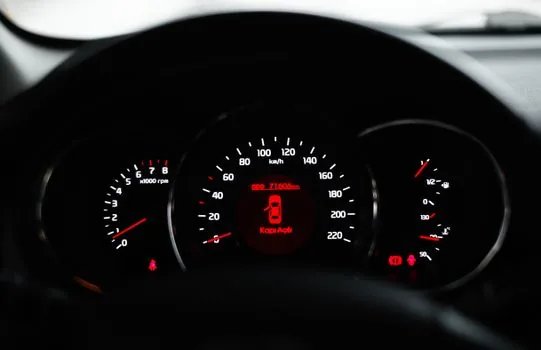 a compact car parked in front of a small Korean shop, fuel gauge and dashboard visible through the window, soft daylight, editorial photography, no faces