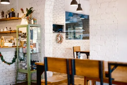 a cozy small Korean neighborhood shop interior at opening time, owner arranging shelves, soft daylight through the window, editorial photography, no faces