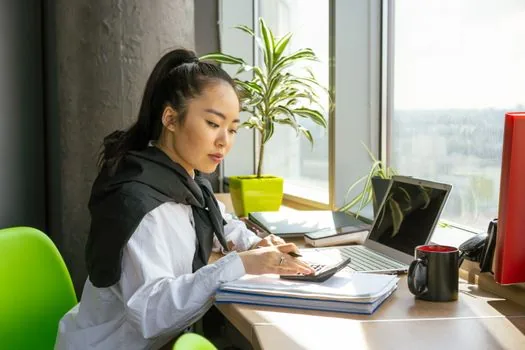 a Korean small business owner's desk with a laptop showing a tax form, stacks of paper receipts and a calculator, soft window light, editorial photography, shallow depth of field