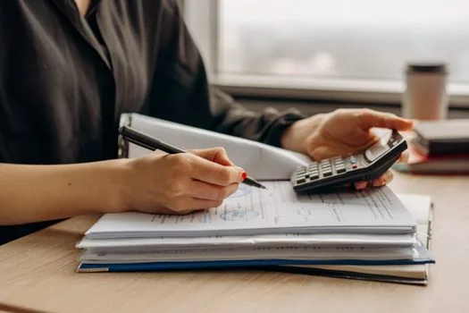 a small business owner reviewing a commercial lease contract at a wooden desk in a shop, calendar and calculator nearby, warm afternoon light through the window, editorial photography, shallow depth of field
