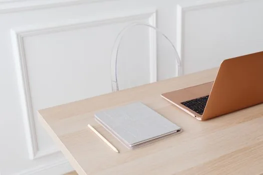 a small business owner's desk with a laptop showing a simple line chart, ledger notebook and a piggy bank, calm home-office mood, editorial photography