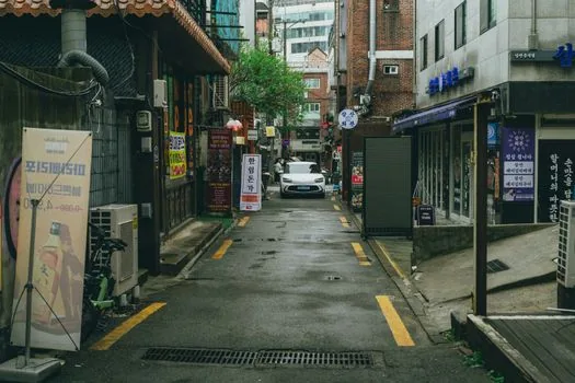 a traditional korean market alley with small shops and hanging signs, morning light, no text