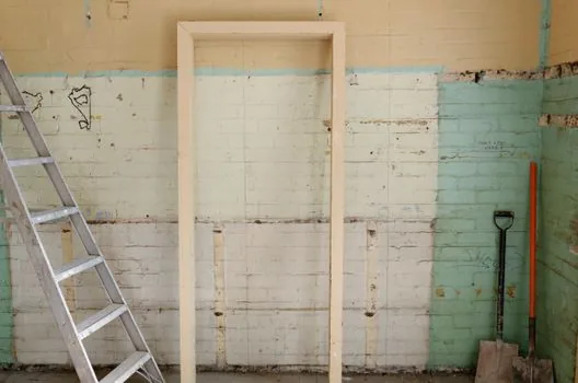 an empty small korean storefront being cleared out for closing, bare walls, workers removing old interior fixtures, daytime natural light, documentary photography