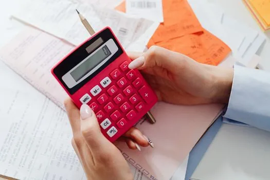 cafe owner reviewing part-time worker schedule and wage calculation, calendar and calculator, warm natural light