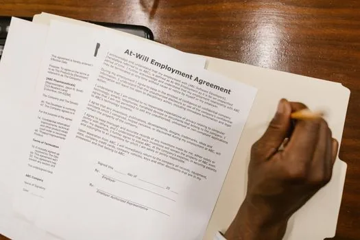 employment contract form with wage and work schedule fields, pen and calculator on small business desk, realistic editorial photo