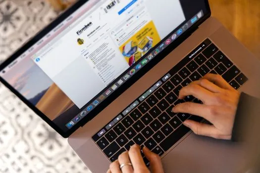 hands typing on a laptop showing an online government insurance application form, tidy home office desk, soft daylight, over-the-shoulder view, editorial photography