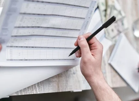 Korean small company owner arranging branch office sales ledgers and tax calendar on desk
