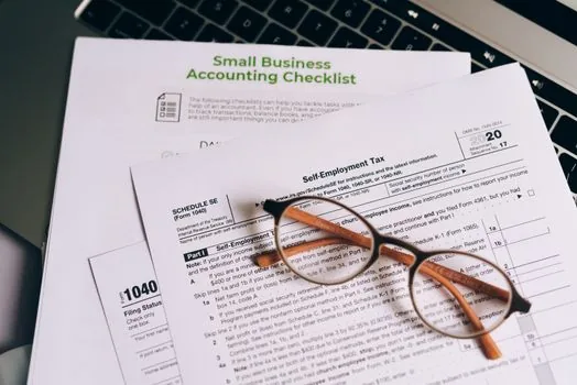 korean tax documents and a laptop showing a spreadsheet on a wooden desk, calm home office mood, soft daylight, over-the-shoulder angle, editorial photography, no text