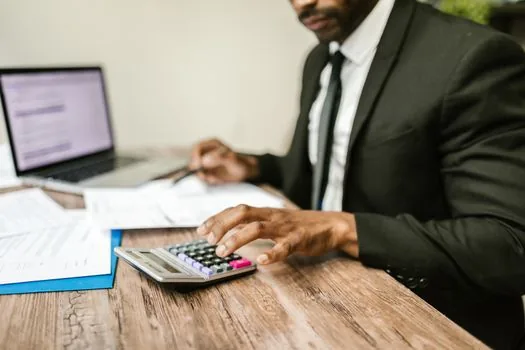 accountant reviewing asset ledger with laptop, vehicle expense folder, depreciation schedule, and calculator