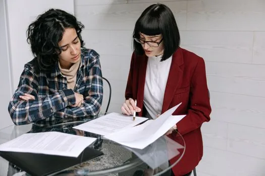 Business owner and HR manager reviewing employment contract clause about Japan visa renewal support with yen calculator