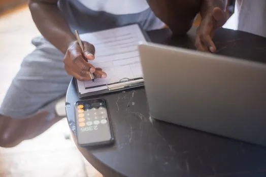 Business owner checking fiscal year selection note beside laptop and calculator, Korean loan document checklist, realistic daylight office photo