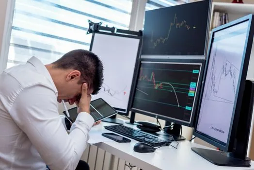 Business owner comparing stock account loss screen, loan repayment notice, and upcoming VAT payment calendar in a clean Korean office