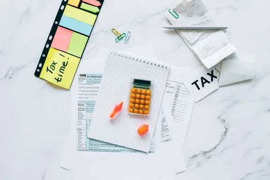 Founder preparing five documents on desk, personal account statement, business account ledger, loan agreement, tax due calendar, and repayment checklist