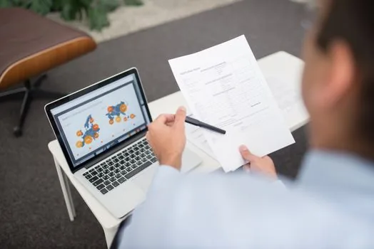 Korean business owner checking court registry kiosk location map on laptop before leaving office, realistic photo no text