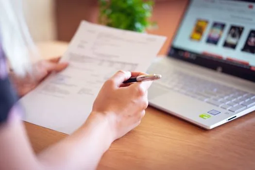 Korean business owner preparing company social insurance certificate with laptop, business registration paper, stamp, and checklist on a bright office desk, no readable private data