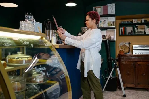Korean cafe manager updating opening hours, menu price and customer review replies on laptop dashboard after store verification, bright counter scene | 매장주 인증 뒤 영업시간과 후기 답글을 관리하는 장면