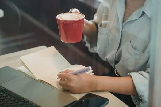 Korean cafe owner checking mobile banking bankbook copy menu and settlement account form on laptop, realistic office photo | 은행 앱 통장사본 메뉴와 정산계좌 신청서를 함께 확인하는 장면