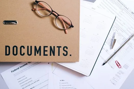 Korean entrepreneur organizing freelancer contracts payroll records and tax payment receipts in folders, bright office desk realistic photo, no brand logos