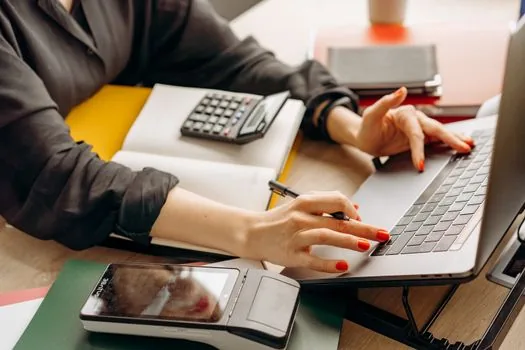 Korean entrepreneur sorting loan application tax certificates, financial statement folder, bank checklist and laptop on clean desk, realistic photo