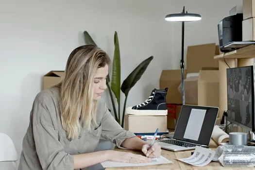 Korean online shop owner checking smart store sales count, laptop dashboard, cardboard parcels, and business conversion checklist on clean desk