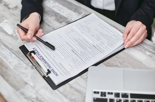 Korean small business administrator checking employment insurance, industrial accident insurance and wage ledger before E-9 permit application, realistic office desk | 고용보험·산재보험과 임금대장을 함께 확인하는 장면