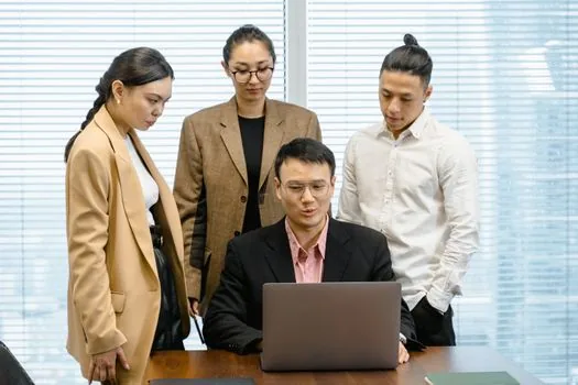 Korean small business finance manager comparing Japan residence renewal fee table and employee visa calendar on laptop