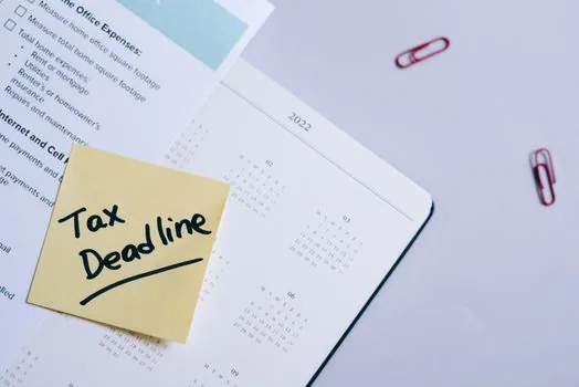 Korean small business owner checking retirement pay statement, payroll folder, and March 10 tax deadline on office calendar, realistic bright office photo no logos