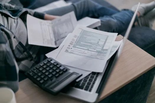 Korean small business owner organizing freelancer invoices, payment ledger and tax calendar on laptop desk, realistic photo | 프리랜서 비용 지급내역과 세무 달력을 함께 정리하는 장면