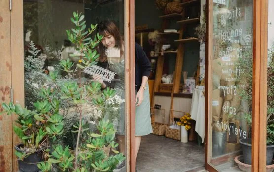 Korean small shop owner searching store name on laptop map service with business registration certificate and storefront photo on desk, bright realistic photo | 카카오맵에서 내 매장 등록 여부를 조회하는 장면