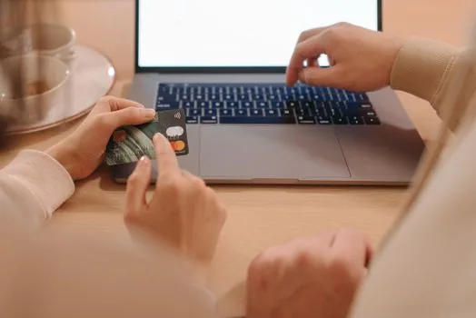 Korean sole proprietor checking Hometax business credit card registration on laptop with credit cards receipts and phone verification memo, realistic office photo | 홈택스 사업용 신용카드 등록 전에 카드와 휴대전화 정보를 정리하는 장면
