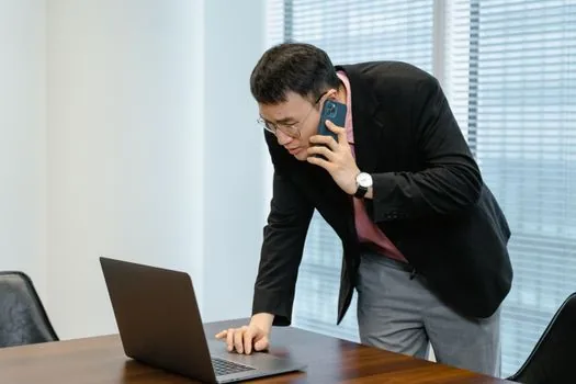 Korean store owner comparing storefront address, phone number and map listing on laptop before requesting admin permission, realistic small business office photo | 기존 카카오맵 장소의 관리자 권한을 요청하기 전 정보를 대조하는 장면