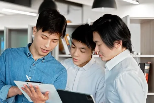 Korean university internship mentoring meeting, student and company mentor checking project schedule on tablet, small regional office, realistic photo | 현장실습 멘토가 학생과 프로젝트 일정을 맞추는 장면