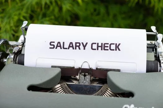 Payroll manager checking employee annual pay totals, tax withholding sheets, non taxable allowance notes, and resignation dates in a spreadsheet