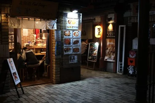 Restaurant owner measuring origin labeling poster next to wall menu board, checking font size and ingredient country list in a small Korean eatery