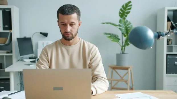 small business owner checking employee travel request form and attendance timestamps on laptop, office desk, realistic business photo, no readable text
