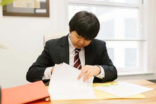 Small company owner preparing English financial certificate and Korean tax documents for overseas partner review, bright office desk, realistic photo