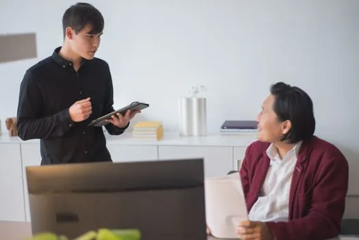 small company owner sorting office staff, sales staff, field worker list and safety training hours on a printed schedule, realistic Korean office photo | 사무직·판매직·현장직 교육시간을 나누는 장면