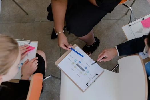 startup founder and HR staff reviewing flexible work policy checklist on conference table, travel receipts and calendar printout, realistic office photo