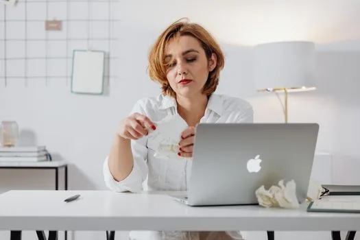 startup founder organizing procurement certificate documents on laptop desk