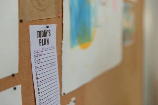 workplace bulletin board with training notice, printed handouts, calendar and checklist, realistic bright office photo