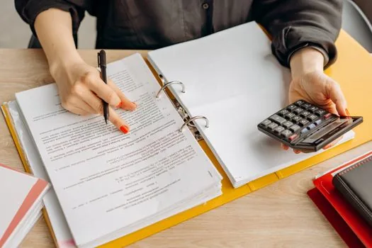 accountant reviewing industry code candidates with sales ledger and business registration copy | 매출 유형과 업종코드 후보를 세무자료와 대조하는 장면